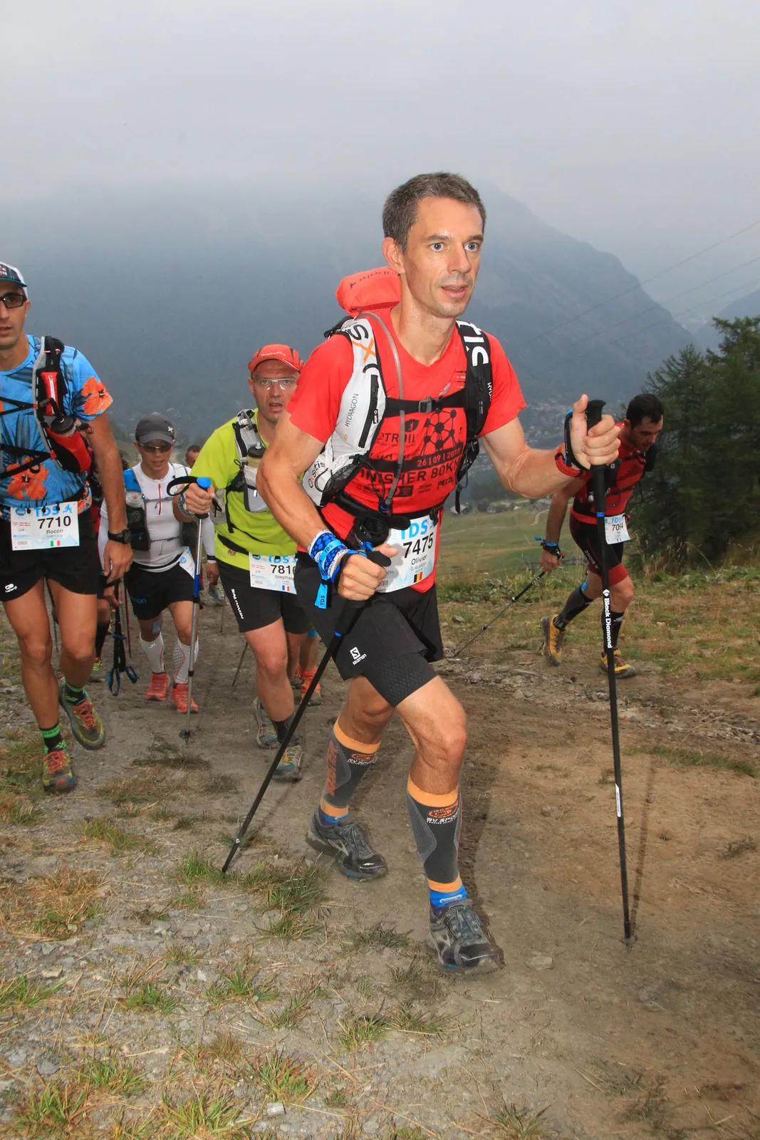 Groupe de coureurs sur une montée de trail en montagne.